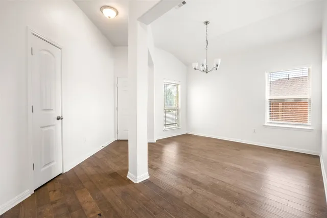 an empty room with wooden floor a ceiling fan and windows