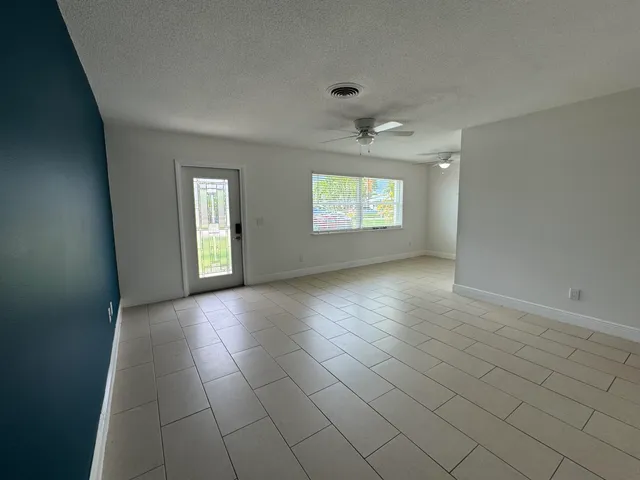 an empty room with windows and chandelier fan