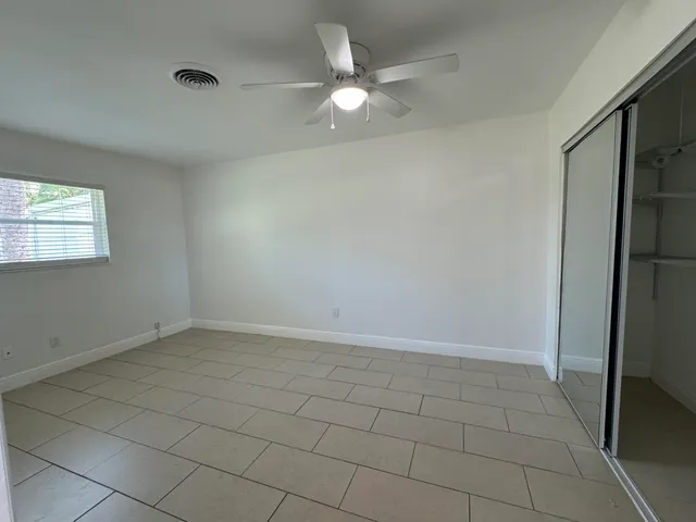 an empty room with windows and a ceiling fan