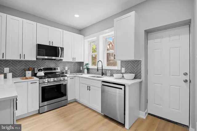 a kitchen with stainless steel appliances granite countertop a stove top oven a sink and a microwave