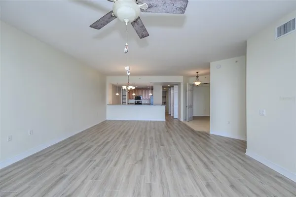 an empty room with wooden floor ceiling fan and windows