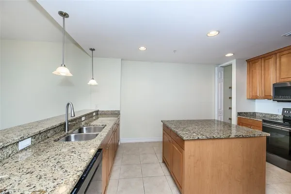a kitchen with kitchen island granite countertop a sink a counter top space and cabinets