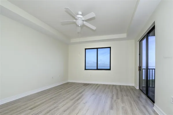 an empty room with wooden floor closet and windows