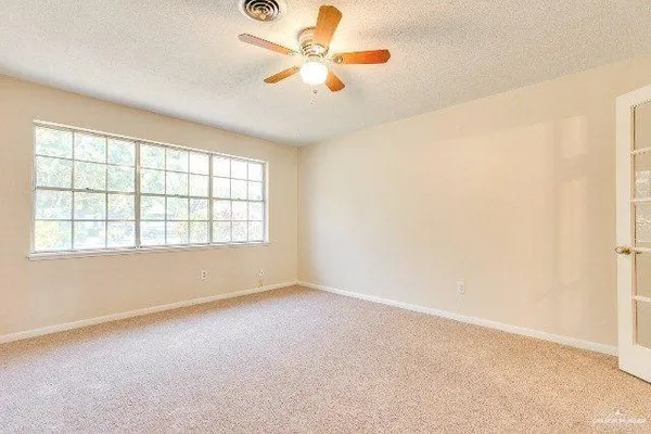 an empty room with chandelier fan and windows
