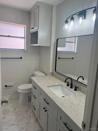 a bathroom with a granite countertop sink a toilet and mirror