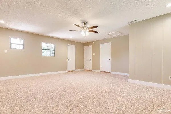 an empty room with windows and fan
