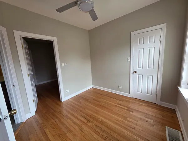 an empty room with wooden floor and a ceiling fan