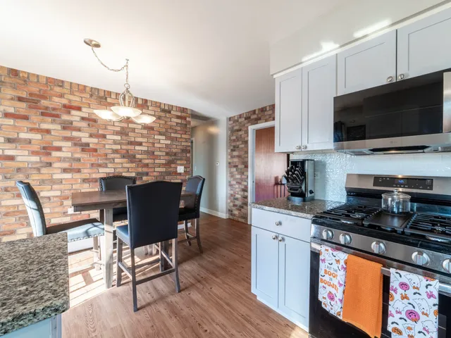 a kitchen with stainless steel appliances kitchen island granite countertop a stove top oven a sink a dining table and chairs