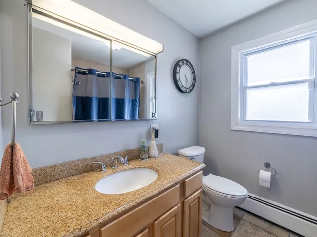 a bathroom with a granite countertop toilet sink and mirror