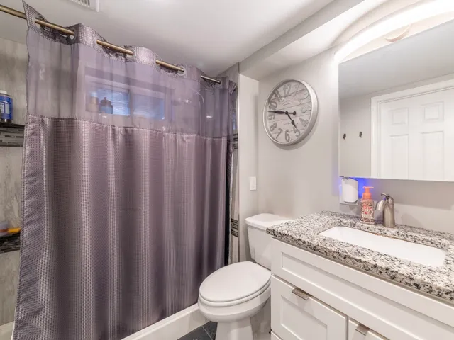 a bathroom with a granite countertop toilet a sink and a mirror