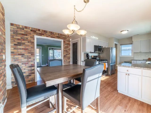 a dining room with wooden floor a chandelier a wooden table and chairs