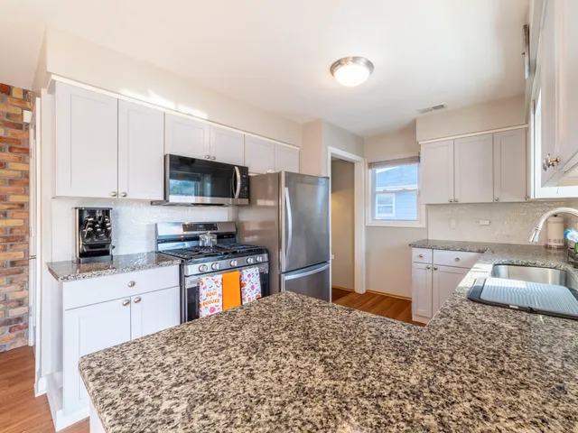 a kitchen with granite countertop a sink stove and refrigerator