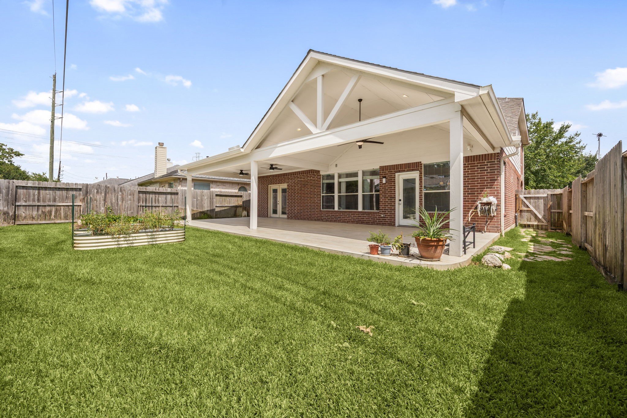 4526 Countrypines Drive Spring, TX 77388 - Photo 34 of 38 A fantastic perspective showcasing the full breadth of the lush, green backyard. The massive covered patio seamlessly bridges indoor and outdoor living, providing a stunning architectural focal point alongside a fully fenced lawn.