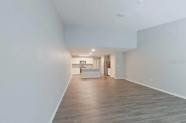 a view of a livingroom with wooden floor and kitchen