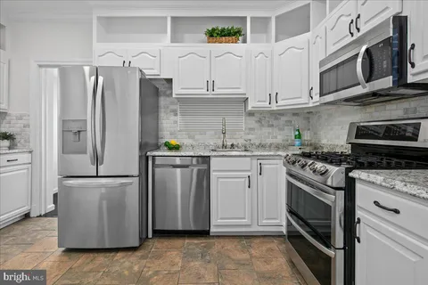 a kitchen with stainless steel appliances granite countertop a refrigerator a stove and a sink