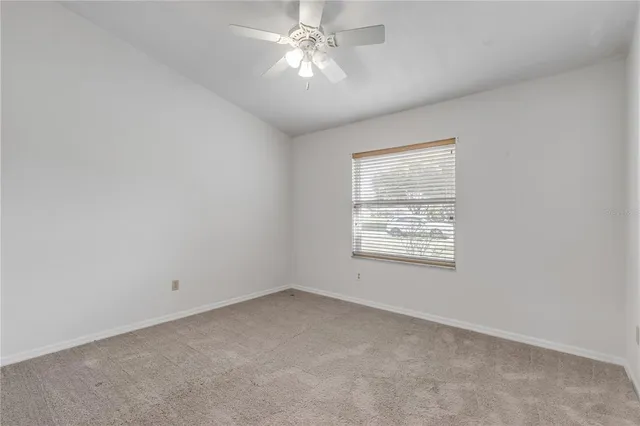 an empty room with a window and a fan