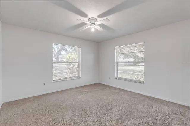 an empty room with windows and fan