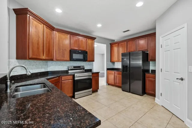 a kitchen with stainless steel appliances granite countertop a refrigerator sink and stove
