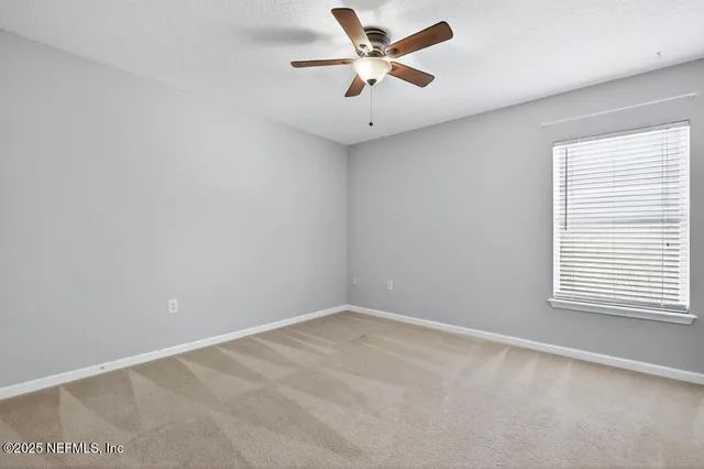 an empty room with a window and a fan