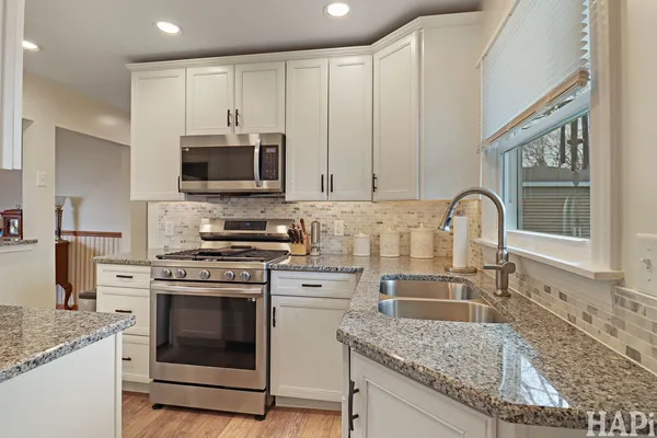 a kitchen with stainless steel appliances granite countertop a stove a sink and a microwave