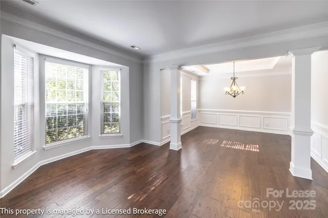 a view of a hallway with wooden floor and a dining room