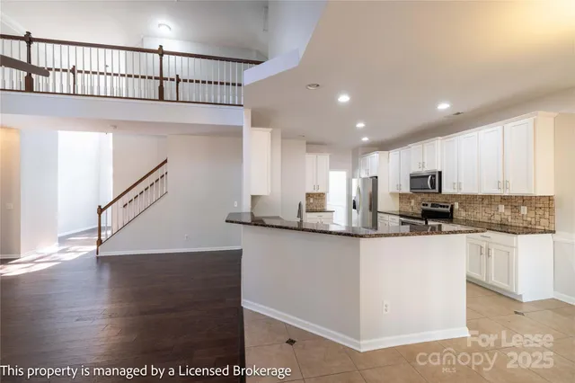 a kitchen with kitchen island granite countertop a sink a stove a refrigerator and a oven