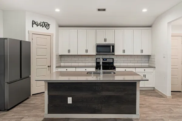 a kitchen with kitchen island a counter top space cabinets and stainless steel appliances