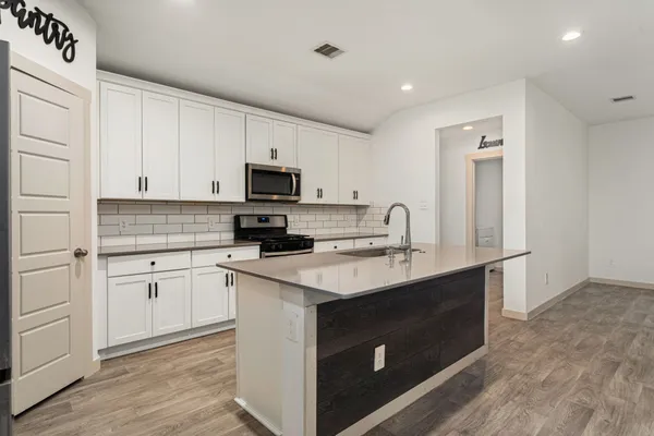 a kitchen with sink a microwave and cabinets