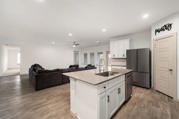 a kitchen with a refrigerator a stove a sink and a oven with wooden floor