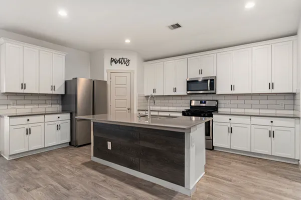 a kitchen with stainless steel appliances granite countertop a stove top oven a sink and a refrigerator