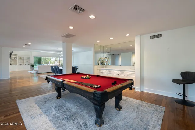a kitchen with stainless steel appliances granite countertop a dining table chairs and a refrigerator
