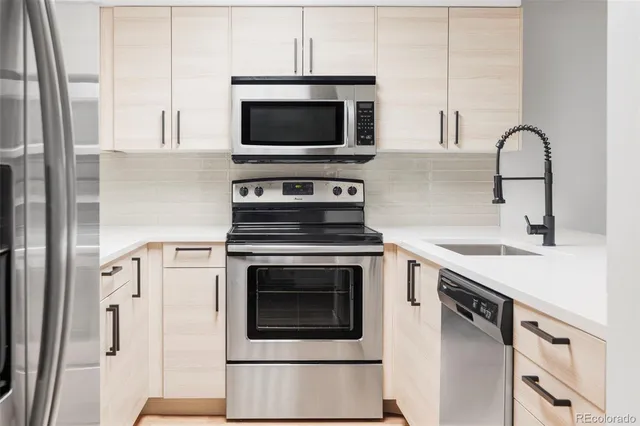 a kitchen with stainless steel appliances a stove microwave and sink