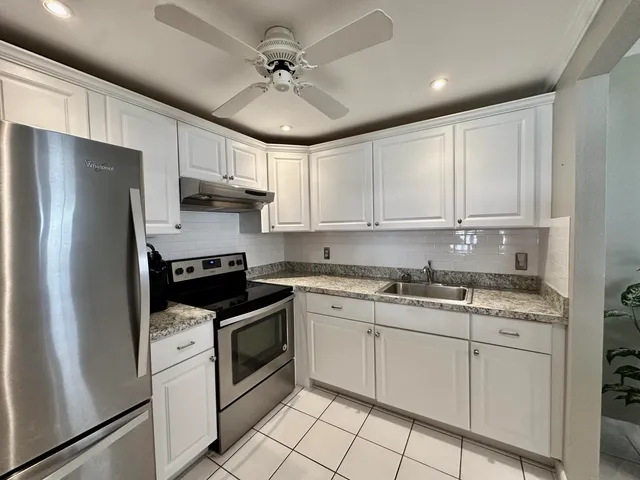 a kitchen with stainless steel appliances granite countertop a stove a refrigerator and a sink