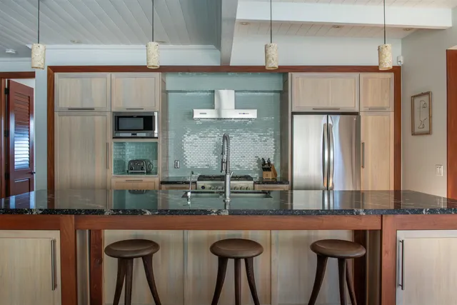 a kitchen with stainless steel appliances granite countertop a table chairs wooden floors and a view of living room