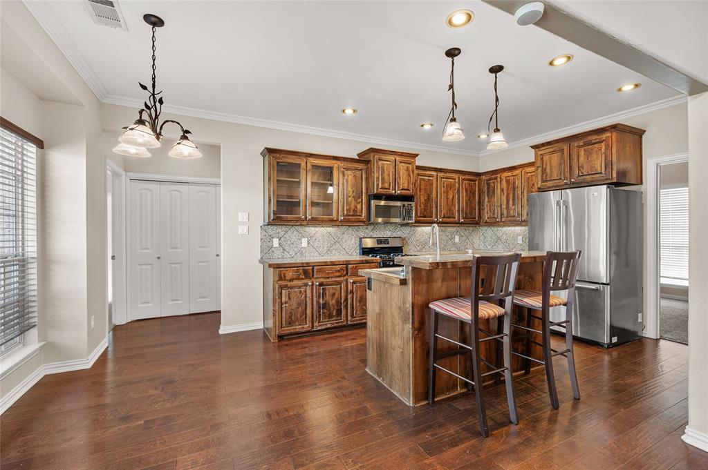 10264 Farmington Road Van Alstyne, TX 75495 - Photo 12 of 39 a kitchen with stainless steel appliances kitchen island granite countertop a refrigerator a stove a microwave oven a sink with island and chairs with wooden floor