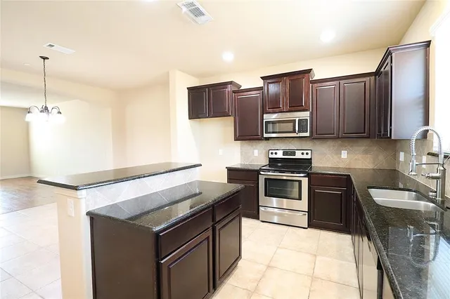 a kitchen with stainless steel appliances granite countertop a sink stove and microwave