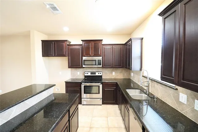 a kitchen with stainless steel appliances granite countertop a sink stove and refrigerator