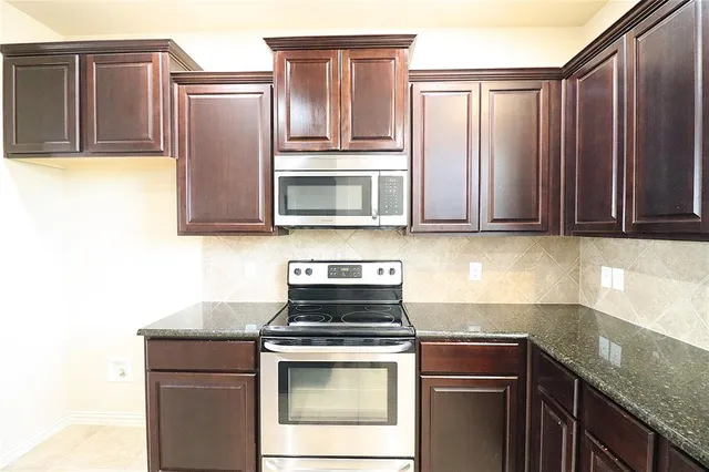 a kitchen with kitchen island granite countertop a sink a stove cabinets and a refrigerator