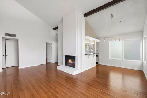 an empty room with wooden floor fireplace and windows