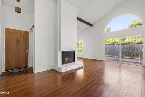 an empty room with wooden floor fireplace and windows
