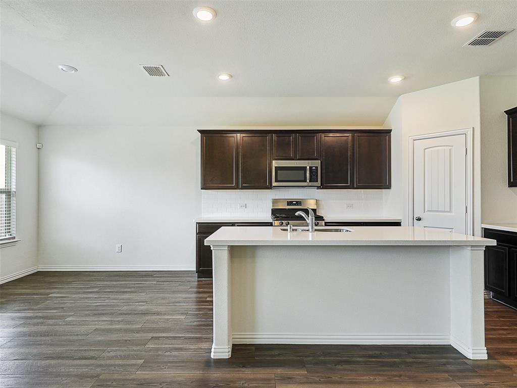 910 Torrey Avenue Princeton, TX 75407 - Photo 13 of 39 a kitchen with stainless steel appliances granite countertop a sink microwave and stove
