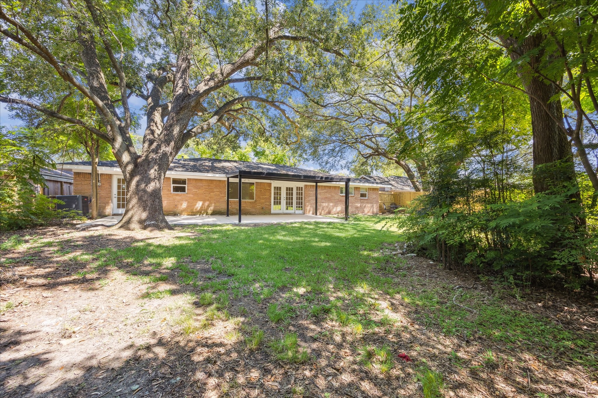 5419 Beechnut Street Houston, TX 77096 - Photo 26 of 28 Backyard retreat with sprawling lawn, mature trees, and patio access—an inviting setting for gatherings and play.