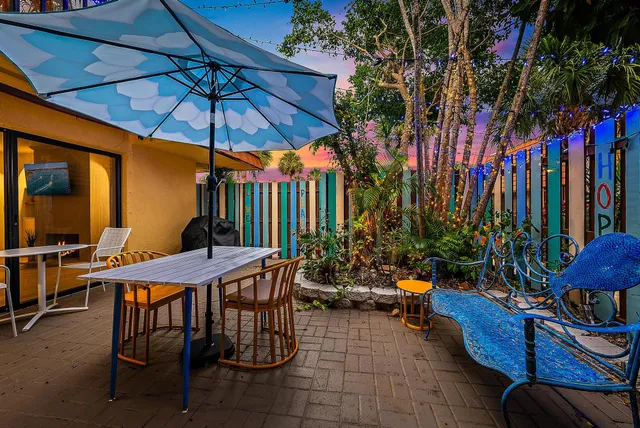a view of a chairs and table under an umbrella in front of house