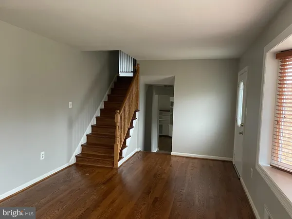 a view of an empty room with stairs and wooden floor