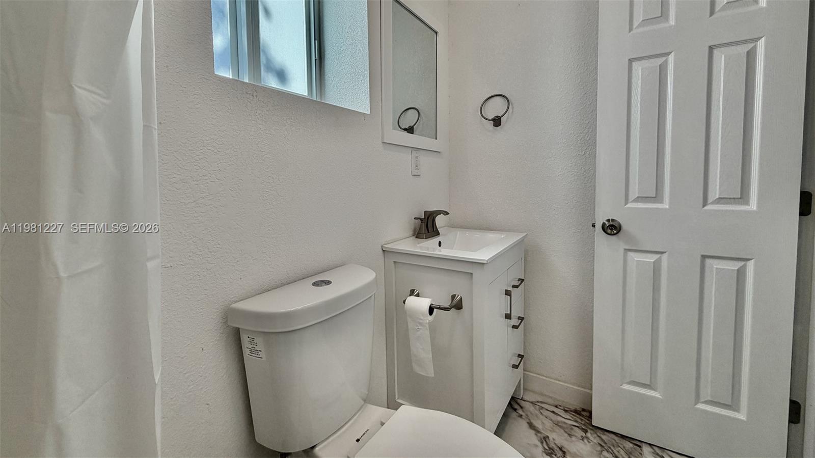 12435 Southwest 42nd Street, Unit 2 Miami, FL 33175 - Photo 7 of 8 a bathroom with a toilet sink and mirror