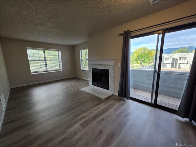 an empty room with wooden floor fireplace and windows