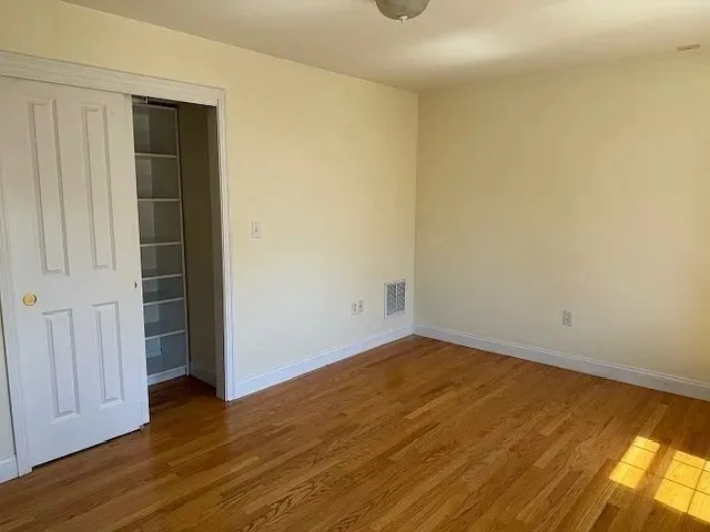 an empty room with wooden floor and closet area