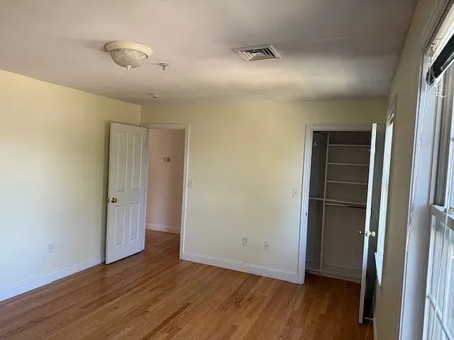a view of an empty room with wooden floor and closet