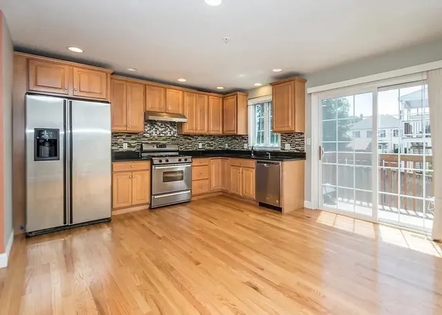 a kitchen with stainless steel appliances granite countertop a refrigerator a sink and a stove top oven