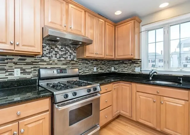 a kitchen with granite countertop a sink a stove and cabinets